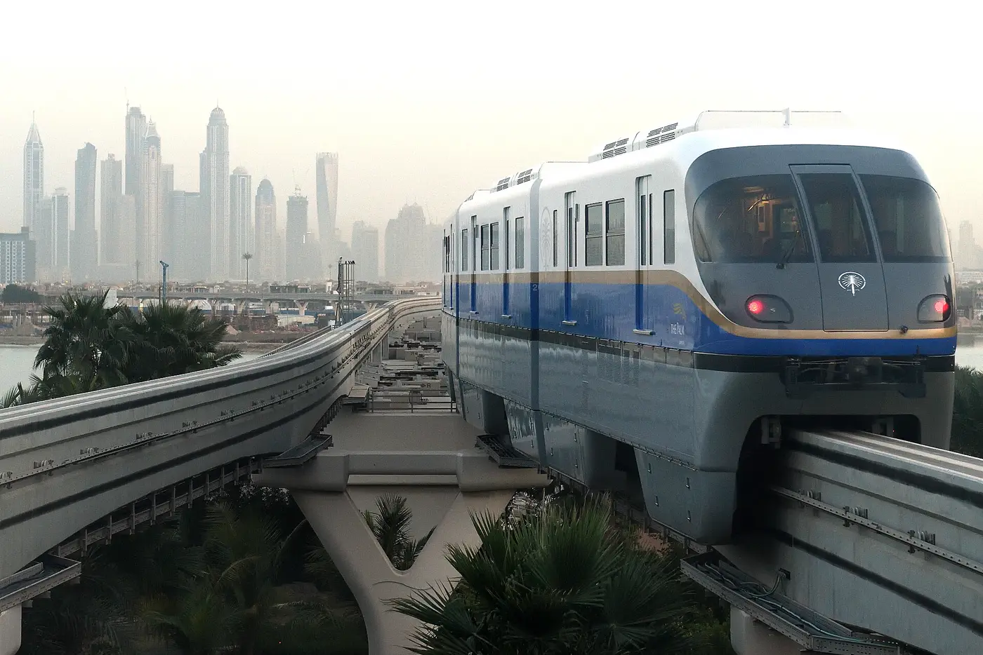 רכבת המונורייל של פאלם ג'ומיירה בשעת בין ערביים, עם קו הרקיע של דובאי מרינה ברקע